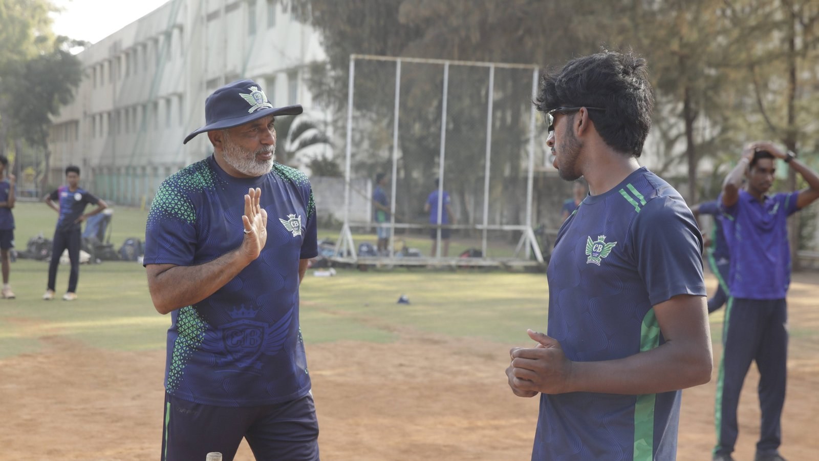 Aarav Rajnikanth discussing cricket technique with a player during training.