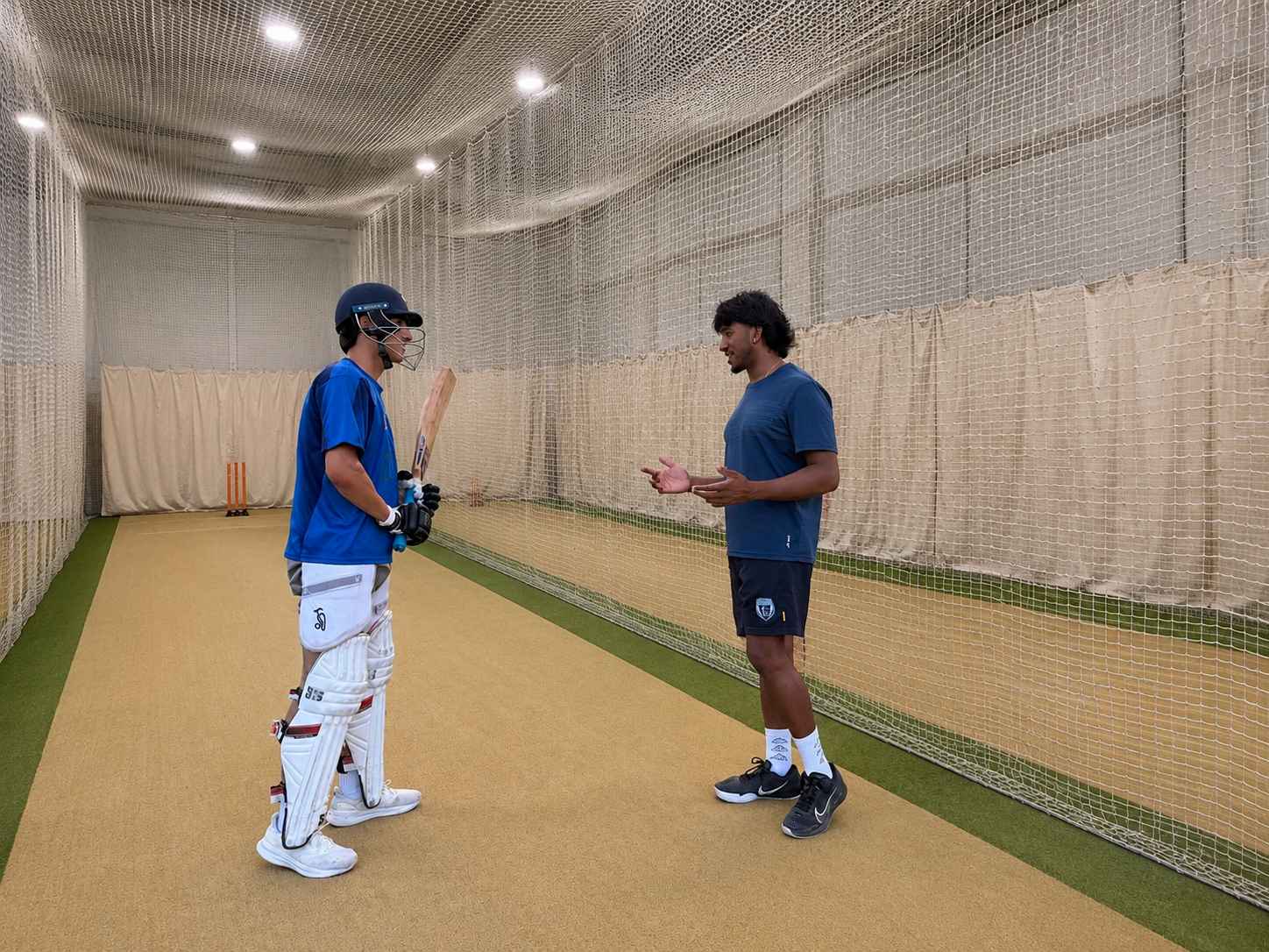 Cricket players training together in outdoor nets.